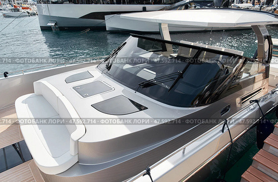 Close-up view of a relaxation area on the open teak deck of an expensive motorboat at sunny day, Monaco yacht show, large boat exhibition, wealth life, table and chairs. Стоковое фото, фотограф Vladimir Drozdin / Фотобанк Лори