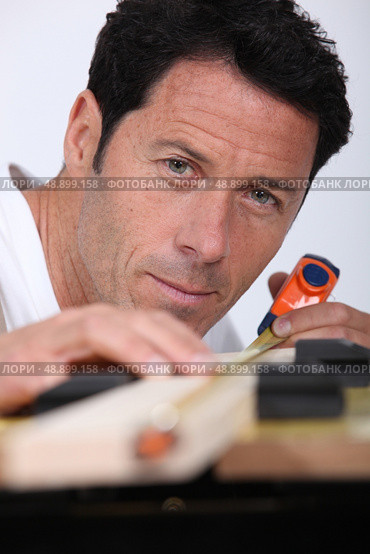 Closeup of a man measuring a piece of wood with a tape measure. Стоковое фото, агентство Ingram Publishing / Фотобанк Лори