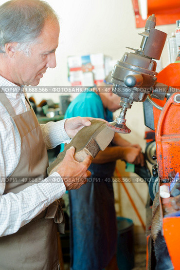 Cobbler grinding heel of shoe. Стоковое фото, агентство Ingram Publishing / Фотобанк Лори