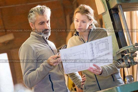 colleagues stood by band saw looking at design drawings. Стоковое фото, агентство Ingram Publishing / Фотобанк Лори