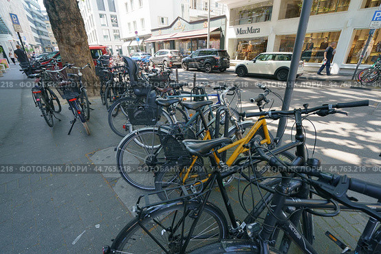 Cologne, Germany -  June 25, 2019: Photography of the cars parking and bikes parking on the city street in hot summer day. Theme of heat touristic time in the city. Редакционное фото, фотограф YuryKara / Фотобанк Лори