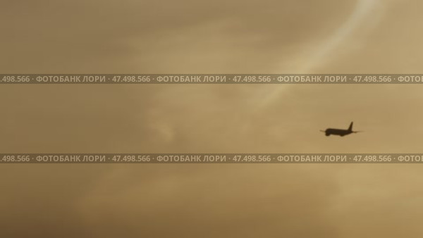 Commercial jet airplane gaining altitude during golden hour sunset, disappearing into hazy atmospheric sky with contrail stretching behind distant aircraft. Стоковое видео, видеограф Данил Руденко / Фотобанк Лори
