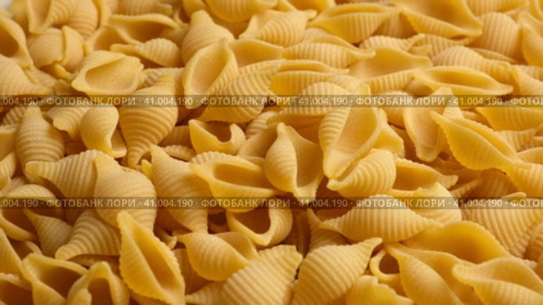 Conchiglie, Shells or Seashells Pasta Wallpaper. Spiral Raw Macaroni from Wheat flour rotating on Turntable. Close Up Top View. Uncooked Pasta Spinning. Full Frame. Food Background. Conchigliette. Стоковое видео, видеограф Марина Демидюк / Фотобанк Лори