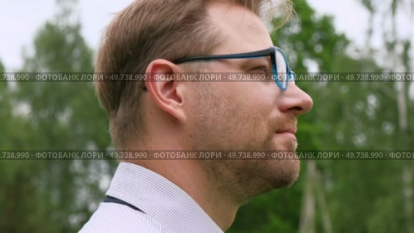 Confident Businessman in Natural Setting. Man stands in front of lush green backdrop. Remote working. Portrait of happy mid adult male wearing formal clothes, shirt and tie, glasses. Find inspiration. Стоковое видео, видеограф Марина Демидюк / Фотобанк Лори