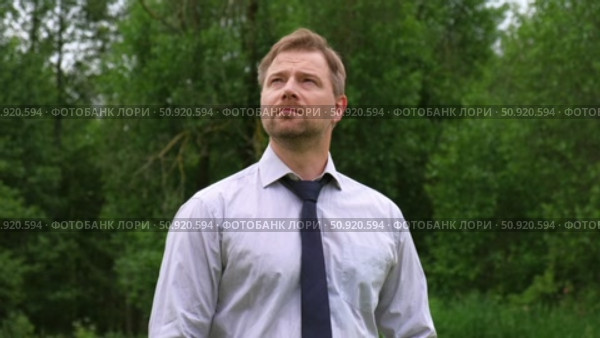 Confident Businessman in Natural Setting. Man stands in front of lush green backdrop. Remote working. Portrait of happy mid adult male wearing formal clothes, shirt and tie, glasses. Find inspiration. Стоковое видео, видеограф Марина Демидюк / Фотобанк Лори