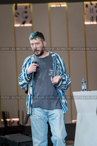 Confident male speaker with microphone at a casual event, engaging audience (2024 год). Редакционное фото, фотограф Антон Гвоздиков / Фотобанк Лори