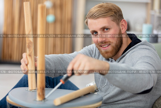 confident man assembles furniture using screwdriver. Стоковое фото, агентство Ingram Publishing / Фотобанк Лори