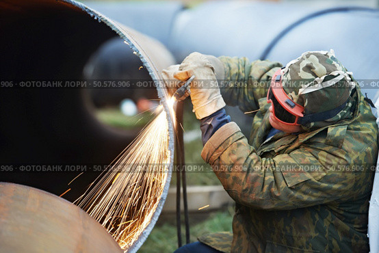 Construction Welder worker in protective glasses cutting metal pipe at building site with welding flame torch cutter. Стоковое фото, агентство Ingram Publishing / Фотобанк Лори
