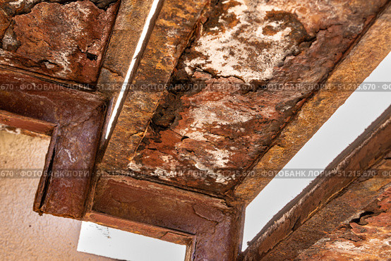 Corroded metal support frame under a porch, with visible decay and loss of structural integrity due to long-term weather exposure. Стоковое фото, фотограф Дмитрий Коростылев / Фотобанк Лори