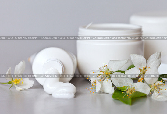 Cosmetics on a light background with spring flowers. Hand care cream comes out of the tube, in white jars there are cosmetic products for face and body care. Spring make-up. Still life. Стоковое фото, фотограф Виктория Катьянова / Фотобанк Лори