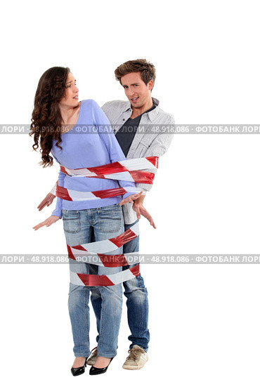 Couple being forcibly held together by caution tape. Стоковое фото, агентство Ingram Publishing / Фотобанк Лори