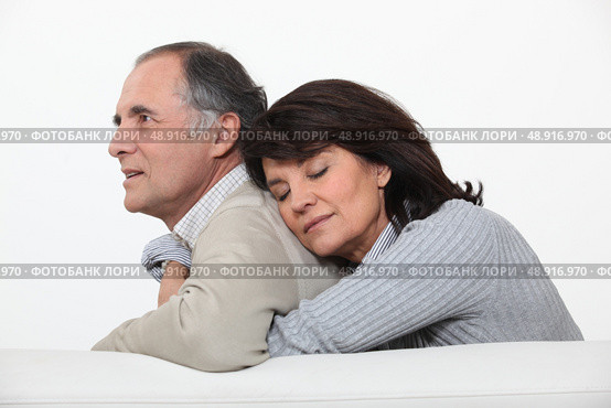 Couple hugging on their couch. Стоковое фото, агентство Ingram Publishing / Фотобанк Лори