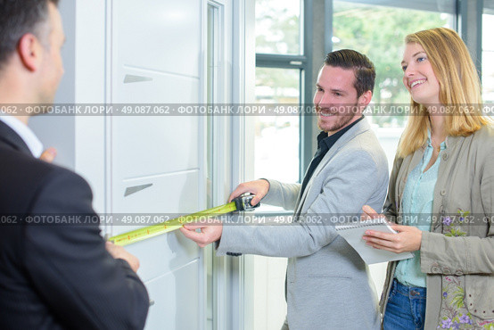 Couple measuring a door, salesman helping. Стоковое фото, агентство Ingram Publishing / Фотобанк Лори