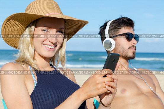 couple on the beach using technological devices. Стоковое фото, агентство Ingram Publishing / Фотобанк Лори