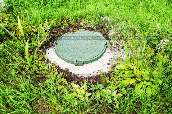 Covered sewer manhole with green plastic cover, sewage system. Sewerage networks. Sanitary sewer system manhole cover. Стоковое фото, фотограф FotograFF / Фотобанк Лори