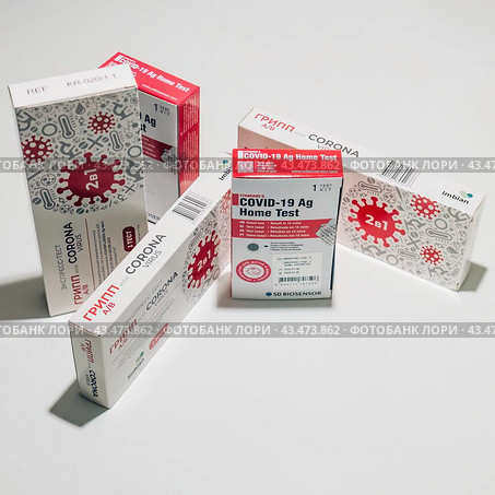 Covid rapid antigen and flu home tests packs on a table. Редакционное фото, фотограф Константин Григорьев / Фотобанк Лори