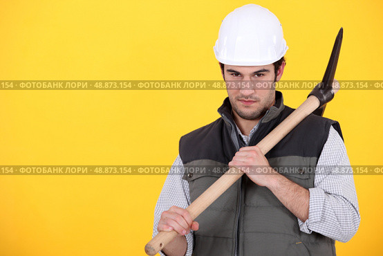 craftsman holding pickaxe against yellow background. Стоковое фото, агентство Ingram Publishing / Фотобанк Лори
