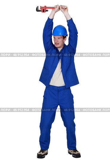 craftsman holding up adjustable spanner. Стоковое фото, агентство Ingram Publishing / Фотобанк Лори