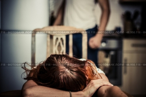 Crying woman in kitchen with abusive partner in the background. Стоковое фото, агентство Ingram Publishing / Фотобанк Лори