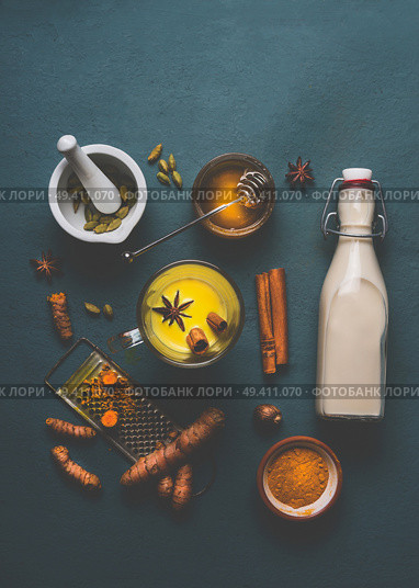 Cup of healthy golden turmeric milk with ingredients: cardamom, fresh turmeric roots, cinnamon, honey and ginger on gray background , top view. Immune boosting remedy , detox and dieting concept. Стоковое фото, агентство Ingram Publishing / Фотобанк Лори