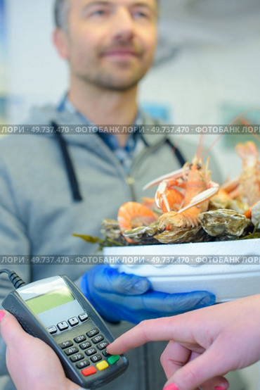 Customer entering code in card machine paying for seafood platter. Стоковое фото, агентство Ingram Publishing / Фотобанк Лори