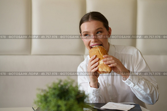 Cute elegant beauty businesswoman biting a sandwich sitting in a modern cafeteria. Cute businesswoman biting a sandwich in a modern cafeteria. Стоковое фото, агентство Ingram Publishing / Фотобанк Лори