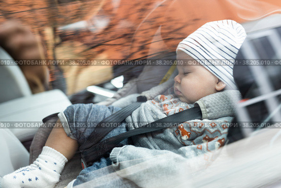 Cute little baby boy sleeping strapped into infant car seat in passenger compartment during car drive. Стоковое фото, фотограф Matej Kastelic / Фотобанк Лори
