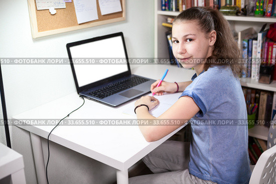 Cute schoolgirl is on distance aducation at home, homeschooling with laptop, isolated monitor screen. Стоковое фото, фотограф Кекяляйнен Андрей / Фотобанк Лори