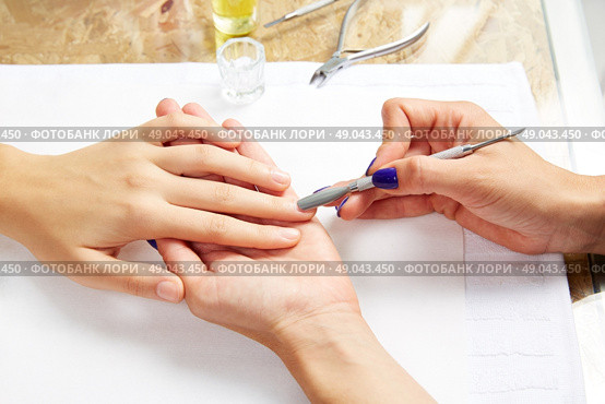 Cuticle pusher tool in nails salon woman hands treatment. Стоковое фото, агентство Ingram Publishing / Фотобанк Лори