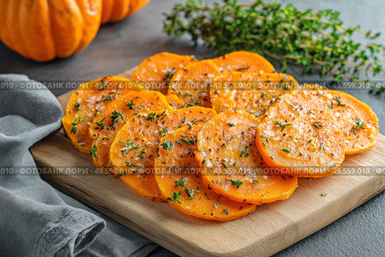 Cutting Fresh Pumpkins on Board. Baked pumpkin. Sliced raw Cucurbita maxima and spices for preparing soup, warm salad, fall dish. Thanksgiving food. Roasted vegetable in olive oil salt pepper, herbs. Стоковое AI-изображение, AI-художник Марина Демидюк / Фотобанк Лори