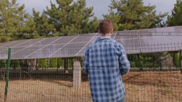 Data analyst and energy consultant standing with his back, analyzing solar system efficiency, evaluating performance, and suggesting improvements. Стоковое видео, видеограф Svetlana Golovco / Фотобанк Лори