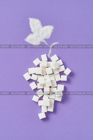 Decorative composition from grape fruit handmade from different types of sweet sugar refined cubes and leaf from granulated sugar on a lavender background, copy space. Flat lay.. Refined sugar cubes as a grape fruit with leaf from granulated sugar. Стоковое фото, агентство Ingram Publishing / Фотобанк Лори