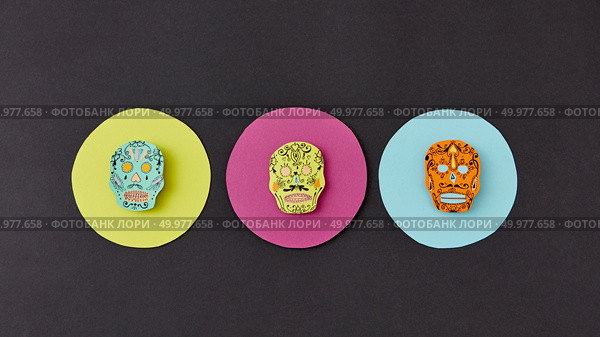 Decorative pattern from round frames with creative handmade skulls on a black paper background. Flat lay. Calaveras simbol of the Mexican holiday of Calaca. Flat lay. Colorful creative Calaca pattern handcraft from colorful round paper with decorative skulls on a black background. Стоковое фото, агентство Ingram Publishing / Фотобанк Лори