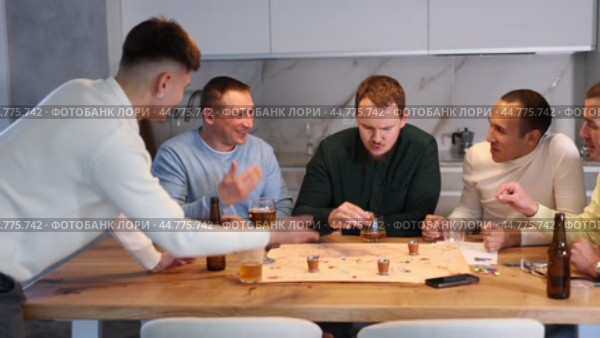 Defeated man taking shot of liquor surrounded by carefree excited male friends playing fun drinking board game during bachelor party at home. Стоковое видео, видеограф Яков Филимонов / Фотобанк Лори