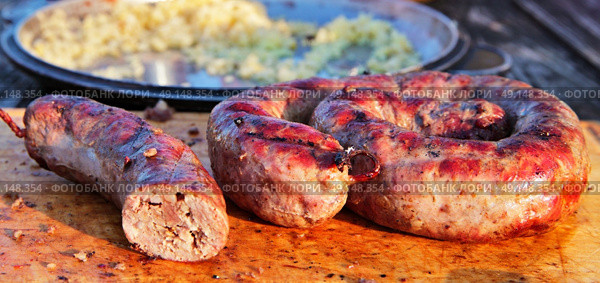 Delicious sausages on wooden plate cooked on barbecue grill. Travel kielbasa cooking. Picnic outdoors. Стоковое фото, агентство Ingram Publishing / Фотобанк Лори