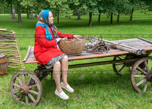 Деревенская женщина едет на ярмарку за товарами на старой деревянной телеге.  Реконструкция сельского образа жизни. Стоковое фото, фотограф Александр Бушков / Фотобанк Лори