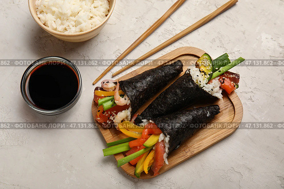 Деревянная доска с вкусными роллами суши, соевым соусом, вареным рисом и палочками для еды на светлом фоне. Стоковое фото, фотограф Pixel_shot / Фотобанк Лори