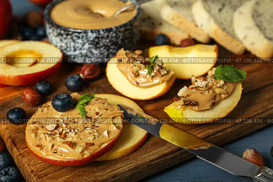 Деревянная доска с вкусными яблочными кружочками и дольками с ореховым маслом, крупным планом. Стоковое фото, фотограф Pixel_shot / Фотобанк Лори