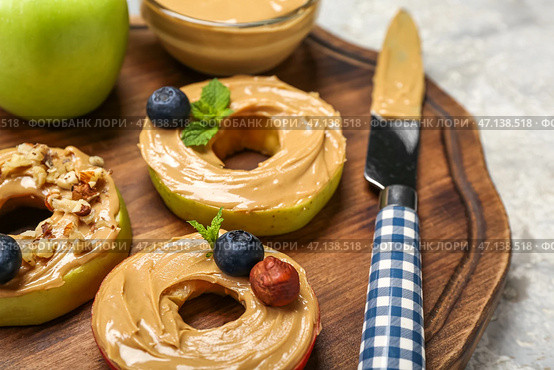 Деревянная доска с вкусными яблочными кружочками с ореховым маслом на столе, крупным планом. Стоковое фото, фотограф Pixel_shot / Фотобанк Лори