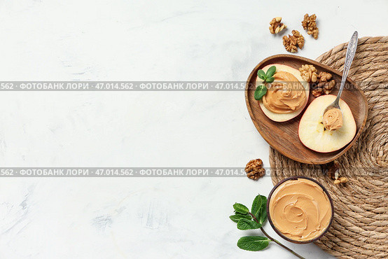 Деревянная миска с яблочными дольками, ореховой пастой, грецкими орехами и мятными листьями на светлом фоне. Стоковое фото, фотограф Pixel_shot / Фотобанк Лори