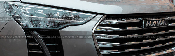 Detail of Haval Jolion car. headlight and logo on radiator front grill (2022 год). Редакционное фото, фотограф Константин Григорьев / Фотобанк Лори