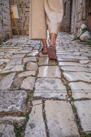 Detail shot of female legs wearing comfortable travel sandals walking on old medieval cobblestones street dring sightseeing city tour. Travel, tourism and adventure concept. Стоковое фото, фотограф Matej Kastelic / Фотобанк Лори