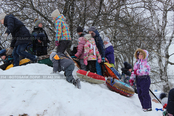 Дети с "ледянками" на снежной горке. Куча-мала. Проводы Масленицы в городе Александрове Владимирской области (2018 год). Редакционное фото, фотограф Елена Орлова / Фотобанк Лори