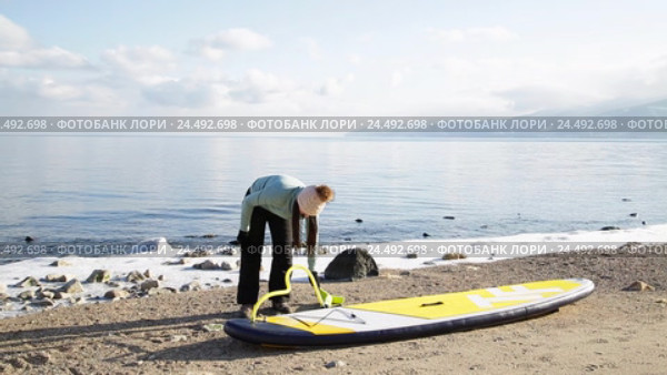 Девушка готовится плавать на sup board по зимнему озеру в сибири (2016 год). Редакционное видео, видеограф Виталий Зверев / Фотобанк Лори