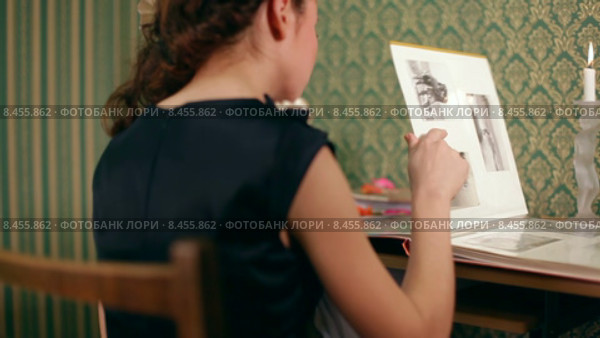 Девушка просматривает фотоальбом. Стоковое видео, видеограф Tatiana Kravchenko / Фотобанк Лори