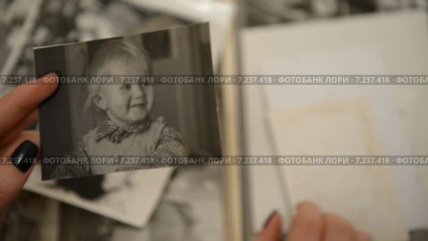 Девушка смотрит старый фотоальбом с детскими фотографиями, период 1970-1980 СССР (2015 год). Редакционное видео, видеограф Mikhail Erguine / Фотобанк Лори
