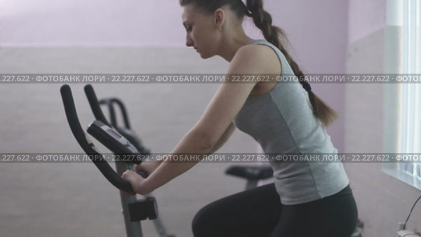 Девушка занимается на велотренажере. Стоковое видео, видеограф Kozub Vasyl / Фотобанк Лори