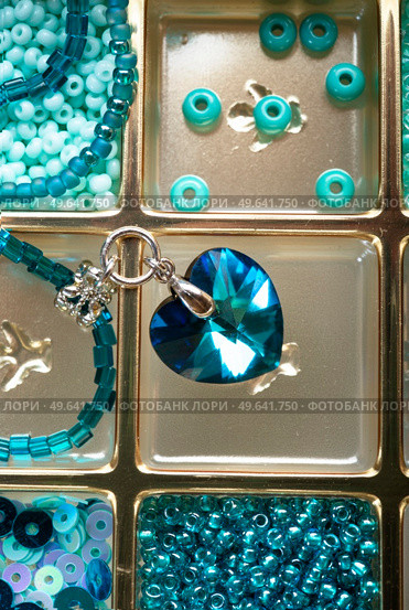 different azure beads and chrystals in box around old style wooden background. close up. Стоковое фото, агентство Ingram Publishing / Фотобанк Лори