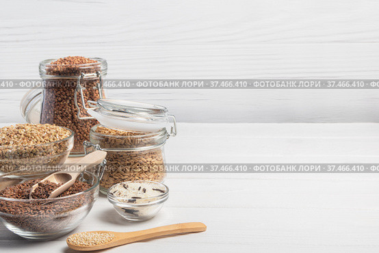 Different cereals on white wooden table. Buckwheat, green buckwheat, whole grain oat, rice, flax seed and quinoa. Horizontal orientation. Copy space. Стоковое фото, фотограф Алдошина Екатерина / Фотобанк Лори