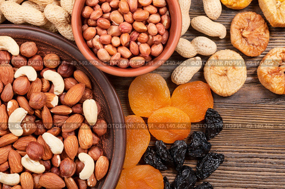 Different nuts in plates and dried fruits on a wooden background. Almond, hazelnut and peanut. Стоковое фото, агентство Ingram Publishing / Фотобанк Лори